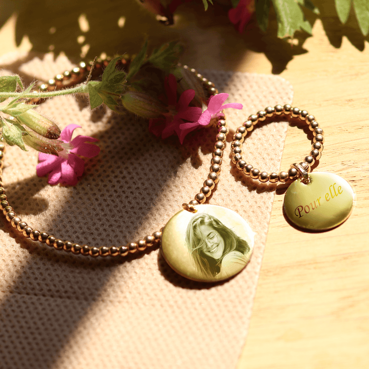 Gravure photo jewelry set featuring a necklace and ring, engraved with 'Pour elle', amidst floral accents.