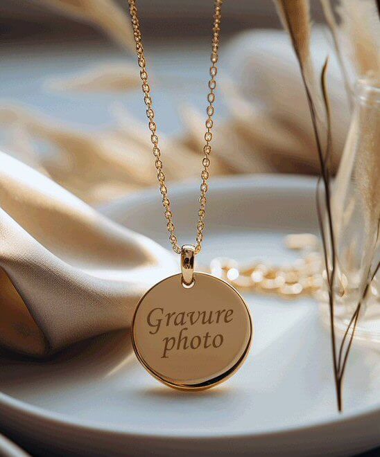 Collier en or avec gravure photo sur bijou, présenté sur une assiette avec tissu doux en arrière-plan.
