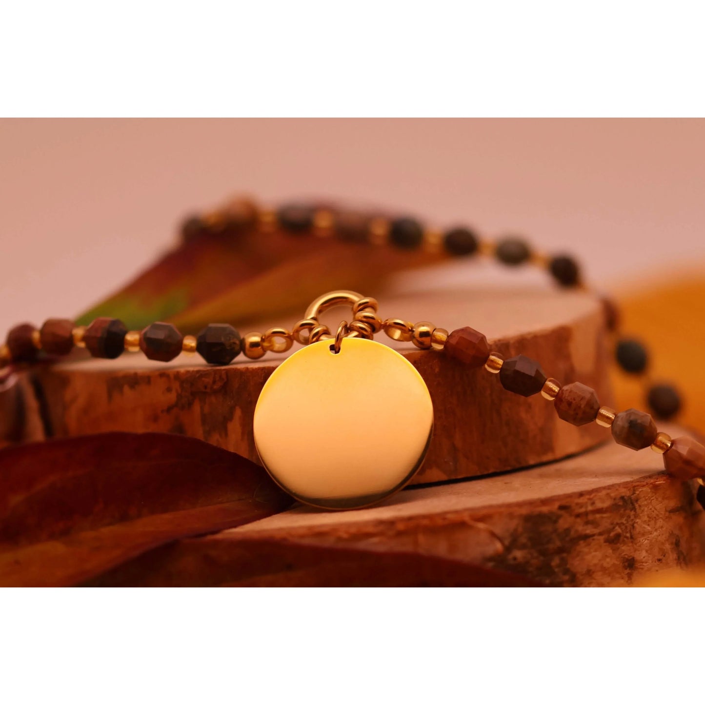 Collier Perles d'Automne avec pendentif gravé en acier inoxydable sur un support en bois.