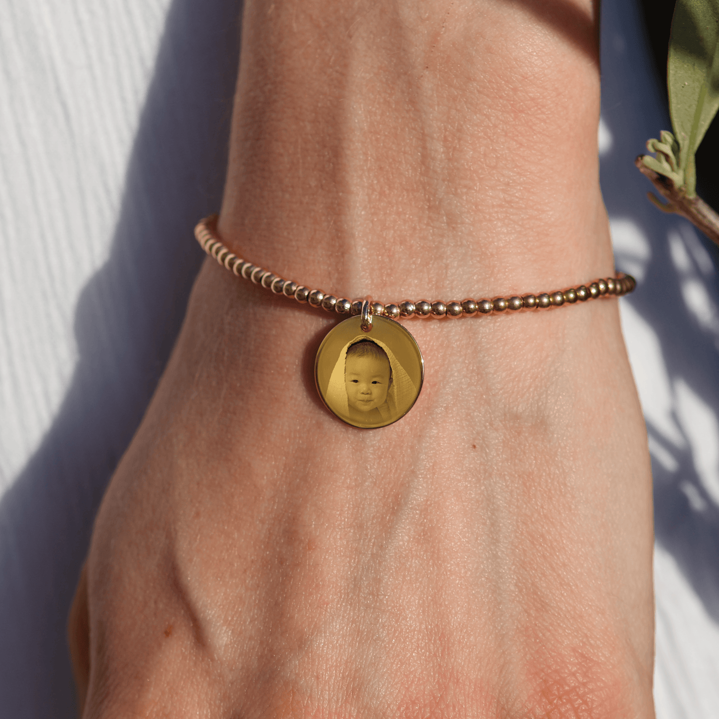 Bracelet en plaqué or personnalisé avec pendentif gravé d'une photo, ajoutant une touche élégante et personnelle.