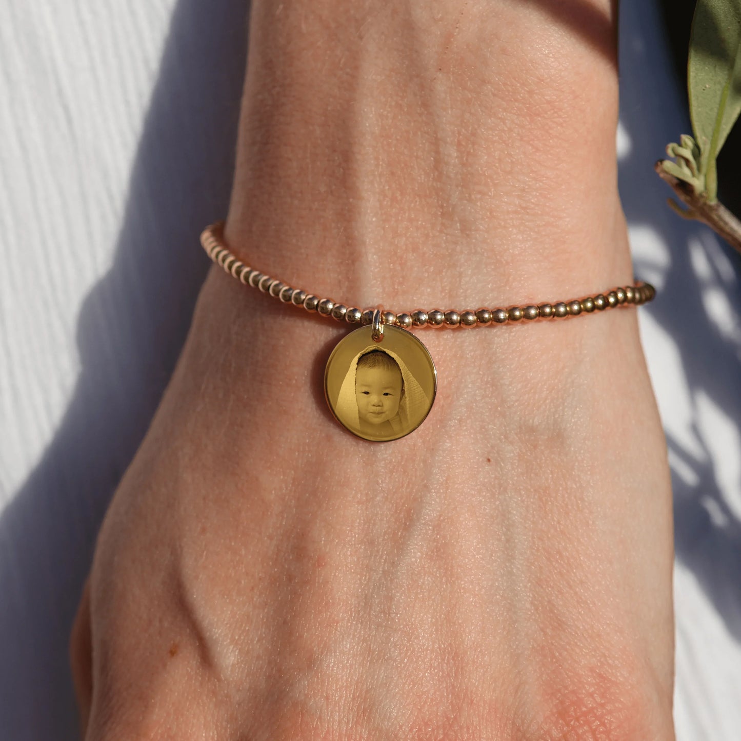 Bracelet en plaqué or personnalisé avec pendentif gravé d'une photo, ajoutant une touche élégante et personnelle.