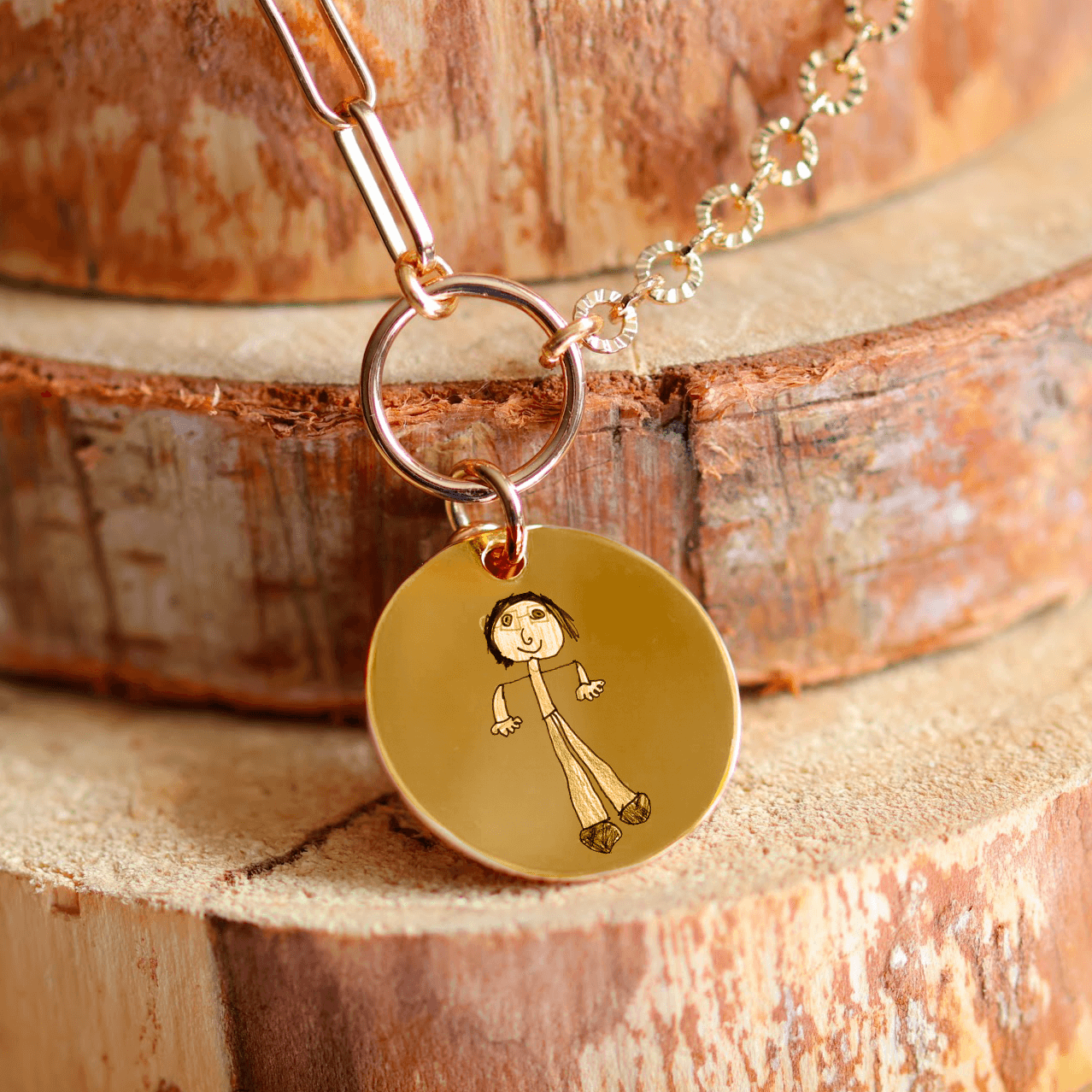 Pendentif rond plaqué or gravé avec un dessin d'enfant sur une chaîne élégante.