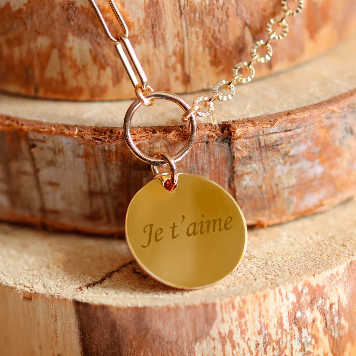 Runde, vergoldete Halskette mit der Gravur „I love you“ auf einem Holzhintergrund. Perfekt für ein personalisiertes Geschenk.