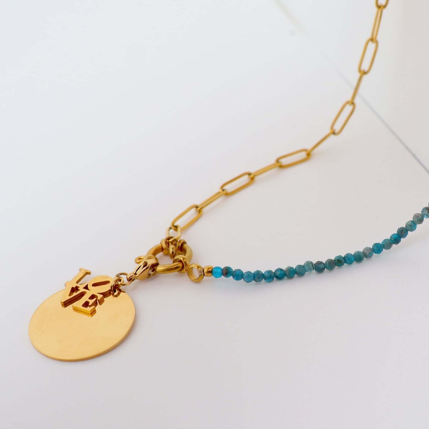 Collier doré avec médaillon gravé 'LOVE' et perles turquoise, élégant et unique.