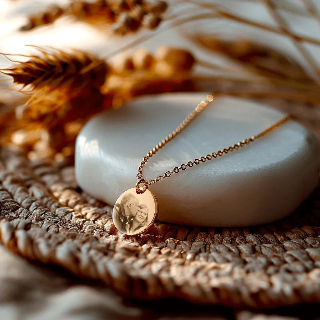 Moyen médaillon rond en acier doré avec gravure personnalisée sur un fond naturel et élégant.