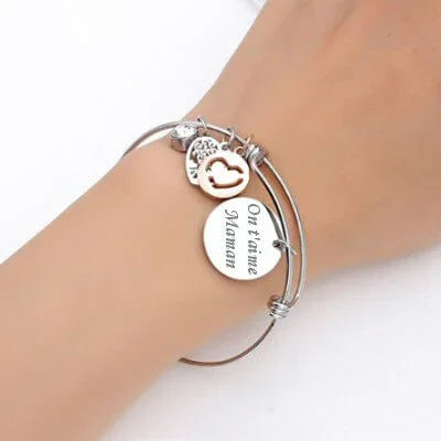 Bracelet jonc argenté avec pendentif rond gravé et charm arbre de vie, porté au poignet