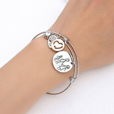 Bracelet avec sa plaque ronde argentée gravée avec un dessin d'enfant.