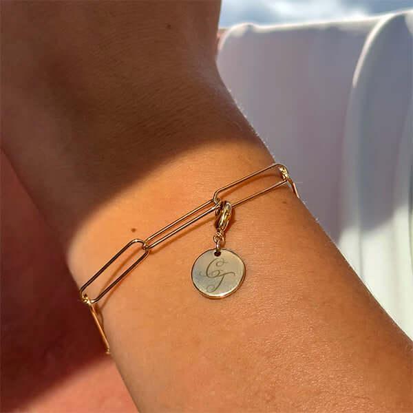 Bracelet mailles plaqué or avec médaille gravée, porté au poignet