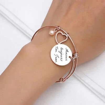 Colgante de corazón de oro personalizado con foto grabada en una delicada pulsera en la muñeca de una mujer