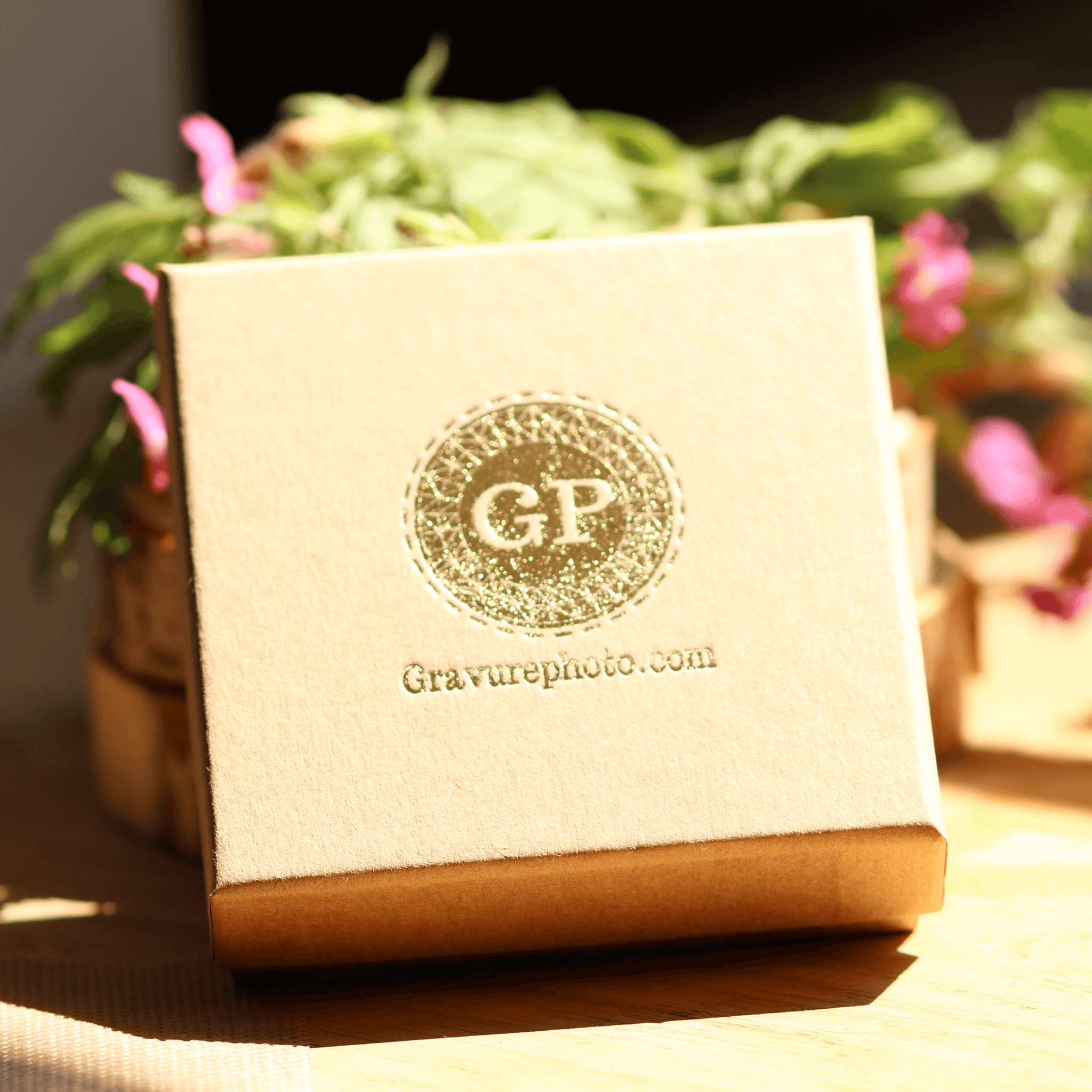 Boîte cadeau élégante pour bracelet mailles personnalisable plaqué or avec logo Gravurephoto.com sur fond flou nature fleurie
