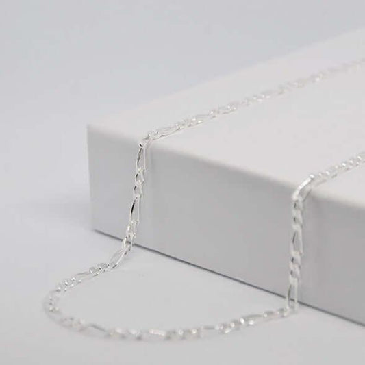 Chaîne en argent élégante posée sur une boîte blanche, bijou GravurePhoto.