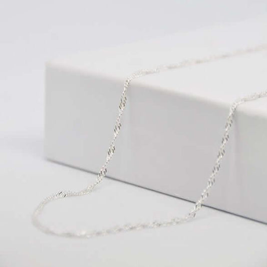 Chaîne torsadée argentée sur fond blanc, bijou GravurePhoto élégant